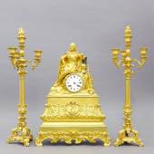 Uhr, Kamin-Set, Pendule und Paar Kerzenleuchter, Frankreich, um 1840 Uhrwerk Pierre Stevenard Boulogne sur Mer. Bronze, feuervergoldet, matt und glänzend. Auf einem reich verzierten, breit ausgestellten Sockel befindet sich ein stilisierter Felssockel mit zentralem Uhrwerk. Auf dem Sockel sitzt ein Edelmann in Rüstung. Rechts daneben befindet sich sein Federhelm und Schwert. Das Uhrwerk ist rückseitig bezeichnet. H 51 x B 36 x T 13,5 cm. Kerzenleuchter, dreiarmig, H.: 57,5 cm. - Pierre Stevenard