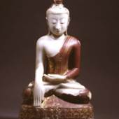 Buddha, bekleidet mit einem einfachen Mönchsgewand, sitzt auf einem Lotusthron. Als Prinz trug er einst schweren Schmuck, weshalb seine Ohrläppchen bis auf seine Schultern reichen. Die 80 cm hohe Marmorfigur ist mit Rotlack und Gold überzogen. Foto: Marianne Franke