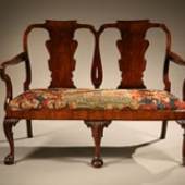 Walnut double chair back settee. c. 1740. Veneered in walnut having shepherds crook arms, a drop in seat with fine18th century French needlepoint, supported on carved cabriole legs with ball and claw carved feet. Height: 39Width: 54 Depth: 22
