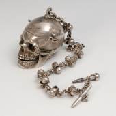 Außergewöhnliche silberne Spindeluhr als Memento Mori. 19. Jh. Undeutlich gepunzt, Gewicht (mit Kette und Schlüssel) 267 g. Gehäuse in Form eines Totenschädels, mit beweglichem Unterkiefer und aufklappbarer Schädeldecke, graviert "Fugit Irreparable Tempus" 