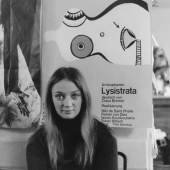 Niki de Saint Phalle vor dem Plakat zu Lysistrata sitzend, 1966 © Foto: unbekannt © 2016 Niki Charitable Art Foundation, All rights reserved.