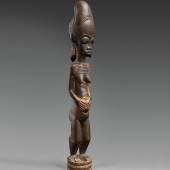 A BAULE FIGURE  Ivory Coast  The standing female with hands on the abdomen, the coiffure with tall top knot and three plaits, keloids on face, neck and body, on circular base, dark glossy patina.  43 cm. high Provenienz  Christie’s London, 7 July 1982, lot 19.  Schätzpreis: €15.000 - €20.000, Ergebnis: 40.000