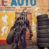 Stéphan Gladieu, 2020, L`homme pneu/Der Reifen-Mann, Künstler: Savant Noir, Stadtviertel Matongue Kimpwanza, Kinshasa (DR Kongo) am 29.8.2020, Fotografie – Fine Art Print
