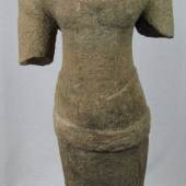 Torso der Khelang - Periode (968-1049), Sandstein, Kambodscha, heutiges Thailand. Torso in archaisch blockhafter Auffassung mit den charakteristischen feinen, parallel verlaufenden Gewandfalten, dem Gürtel und rückseitiger schleifenähnlicher Gewandverknotung. H. Torso 65 cm; Gesamthöhe mit Plinthe 77 cm (originaler, unrestaurierter Zustand). Limitpreis:	9.000 €